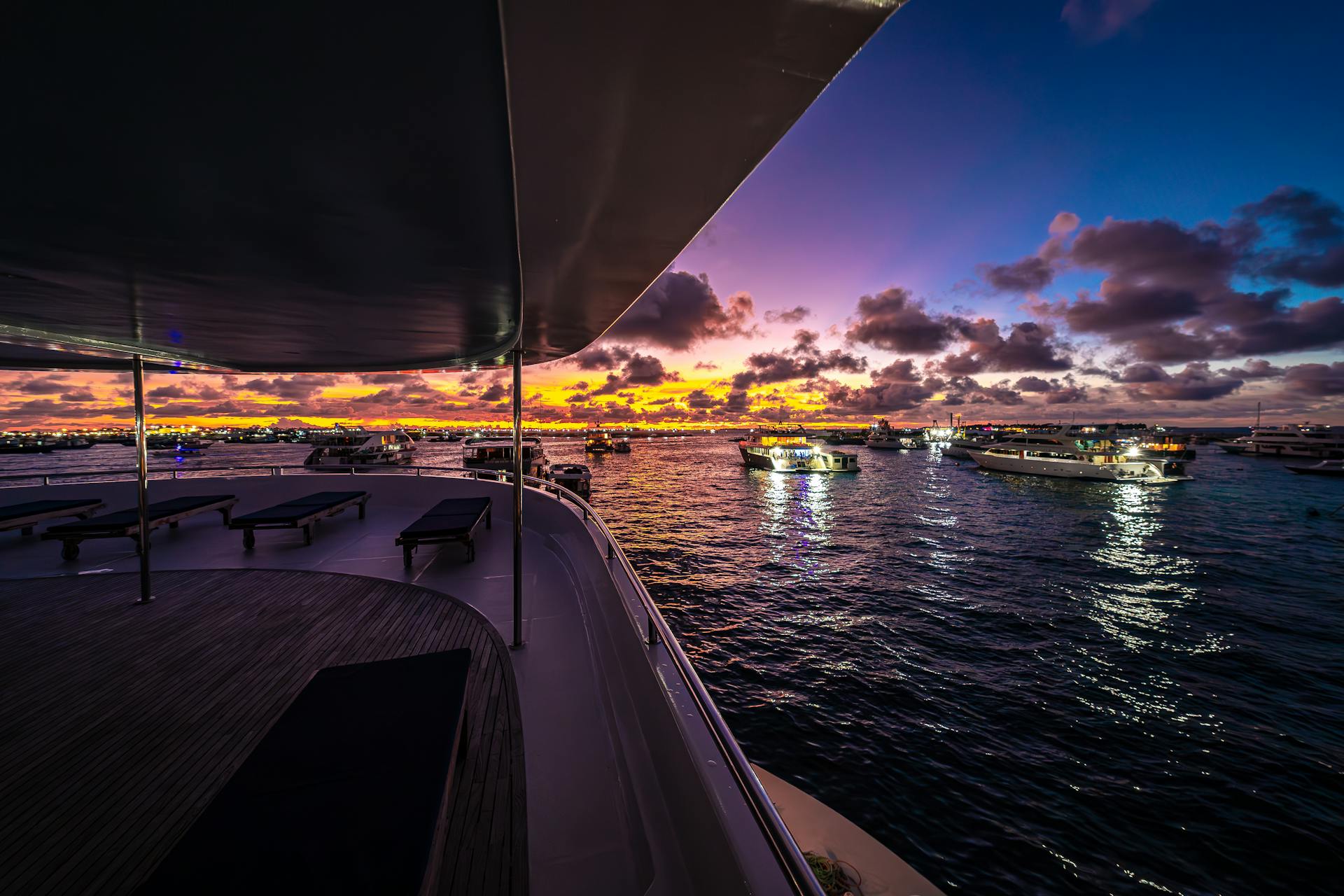 Experience a tranquil sunset cruise aboard a luxury yacht in the Maldives with colorful sky and serene waters.