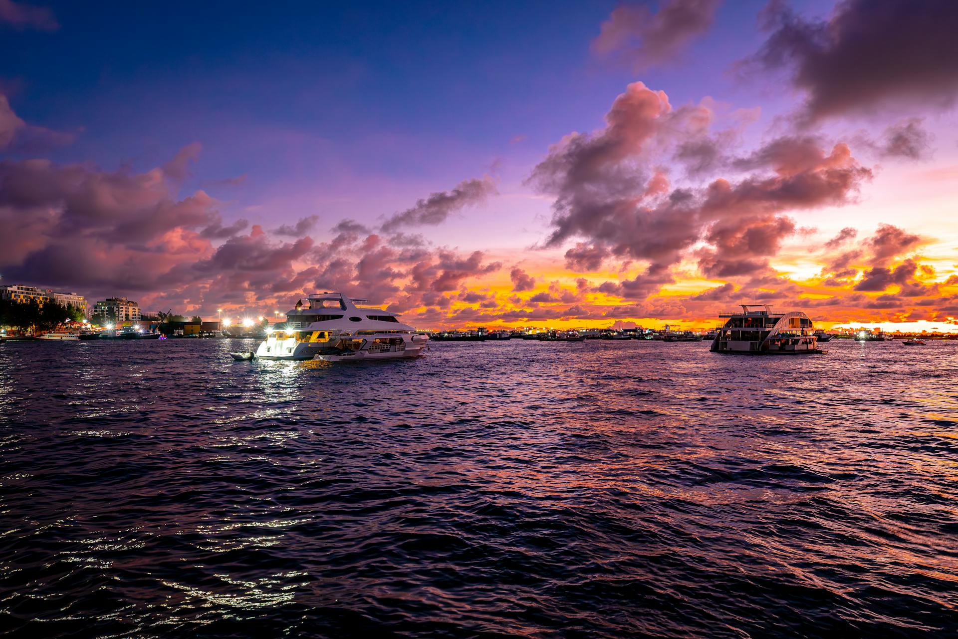 Stunning sunset view of luxury yachts sailing on the calm waters of the Maldives.