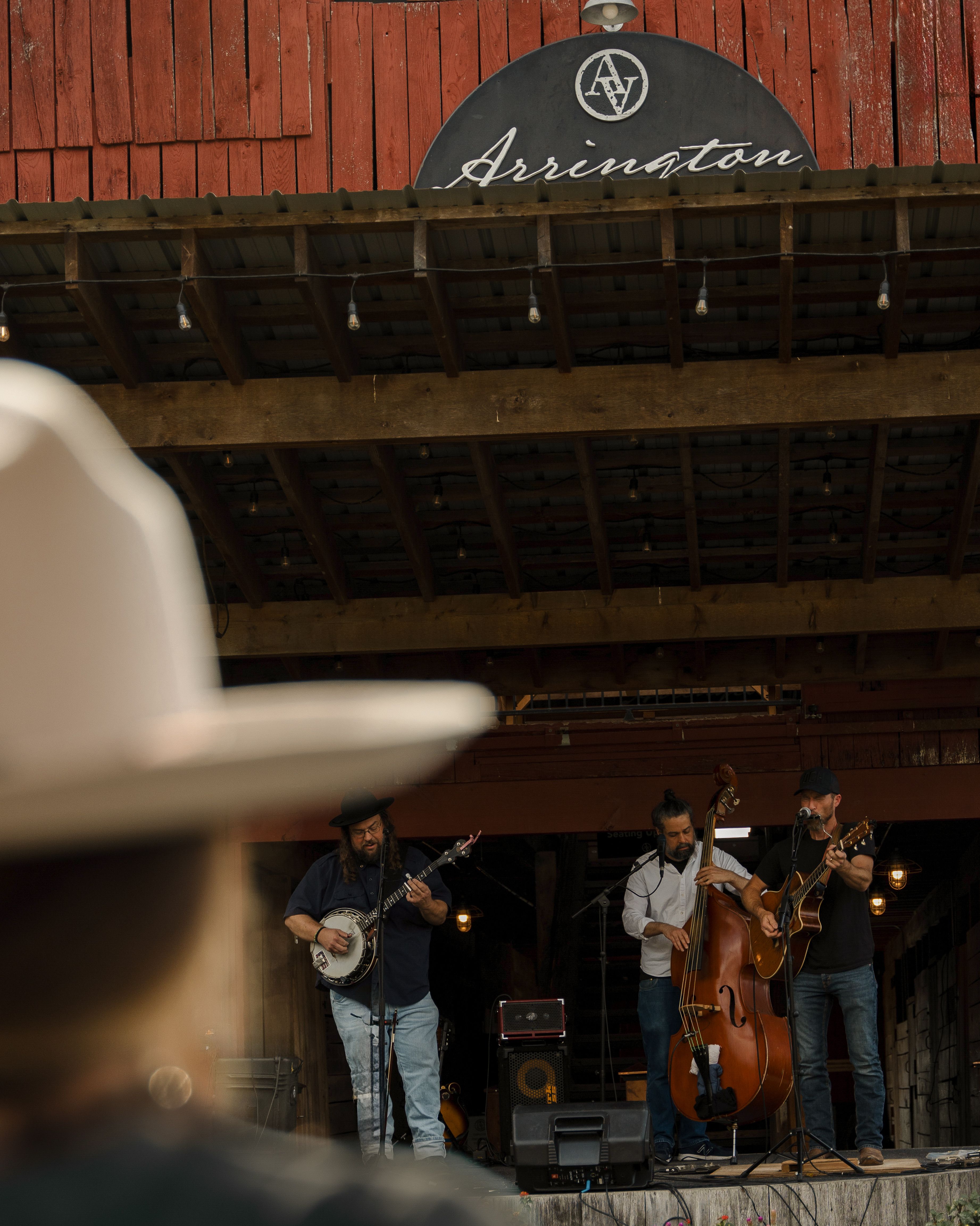 A bluegrass band performing live on a rustic wooden stage at an outdoor venue.