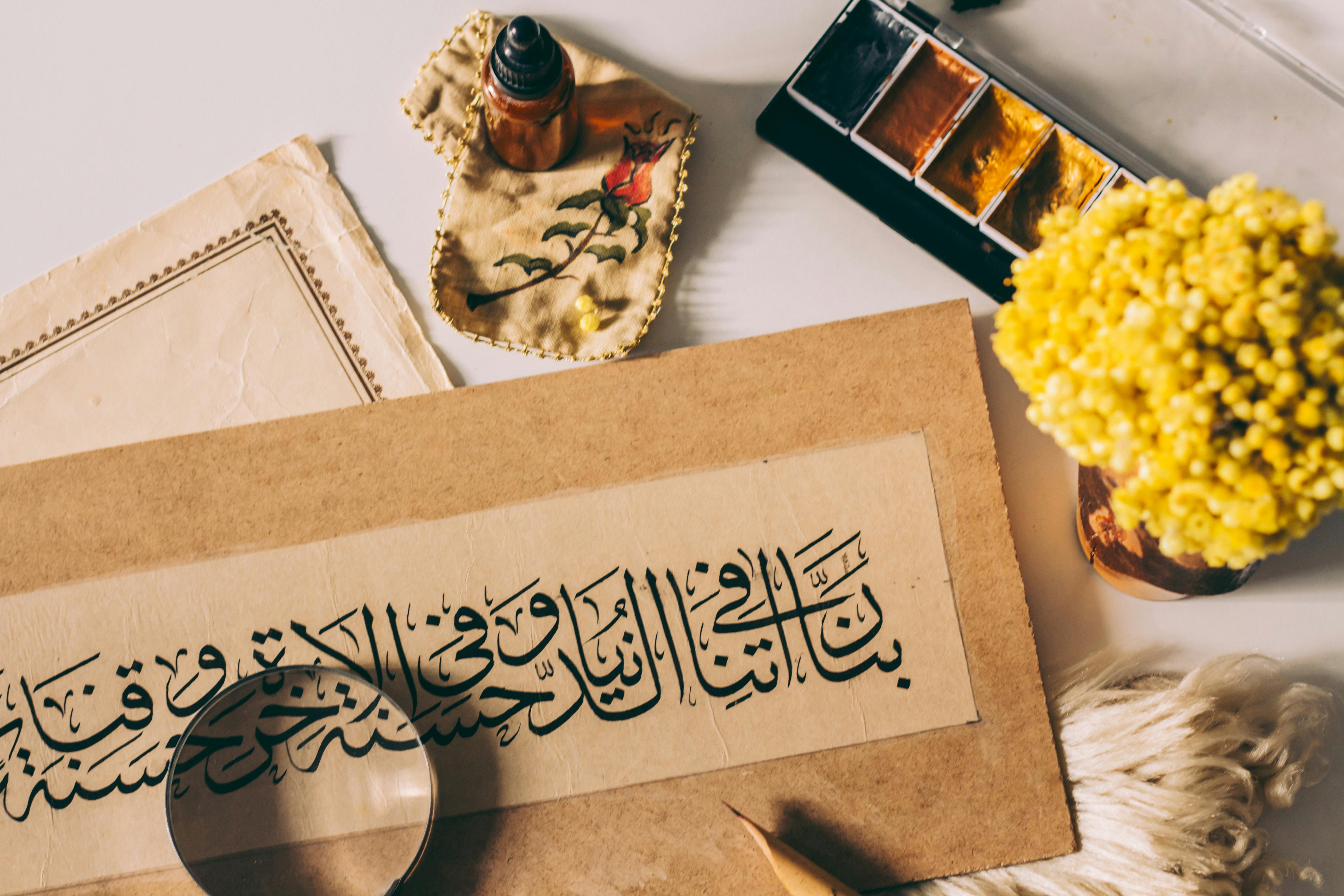 Flat lay of Arabic calligraphy and artistic tools, highlighting traditional and modern art fusion.