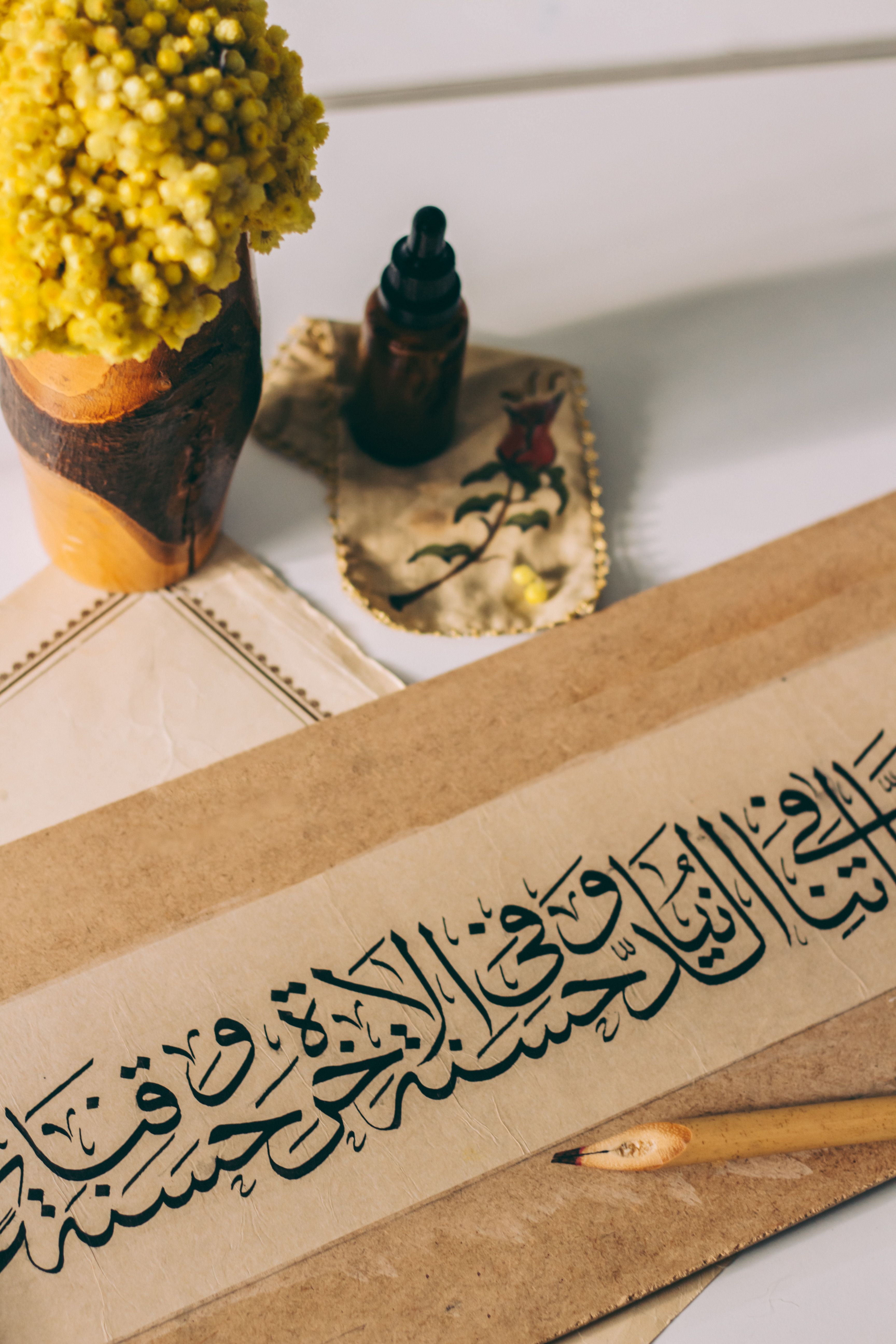 Elegant Arabic calligraphy surrounded by traditional decor and yellow flowers.