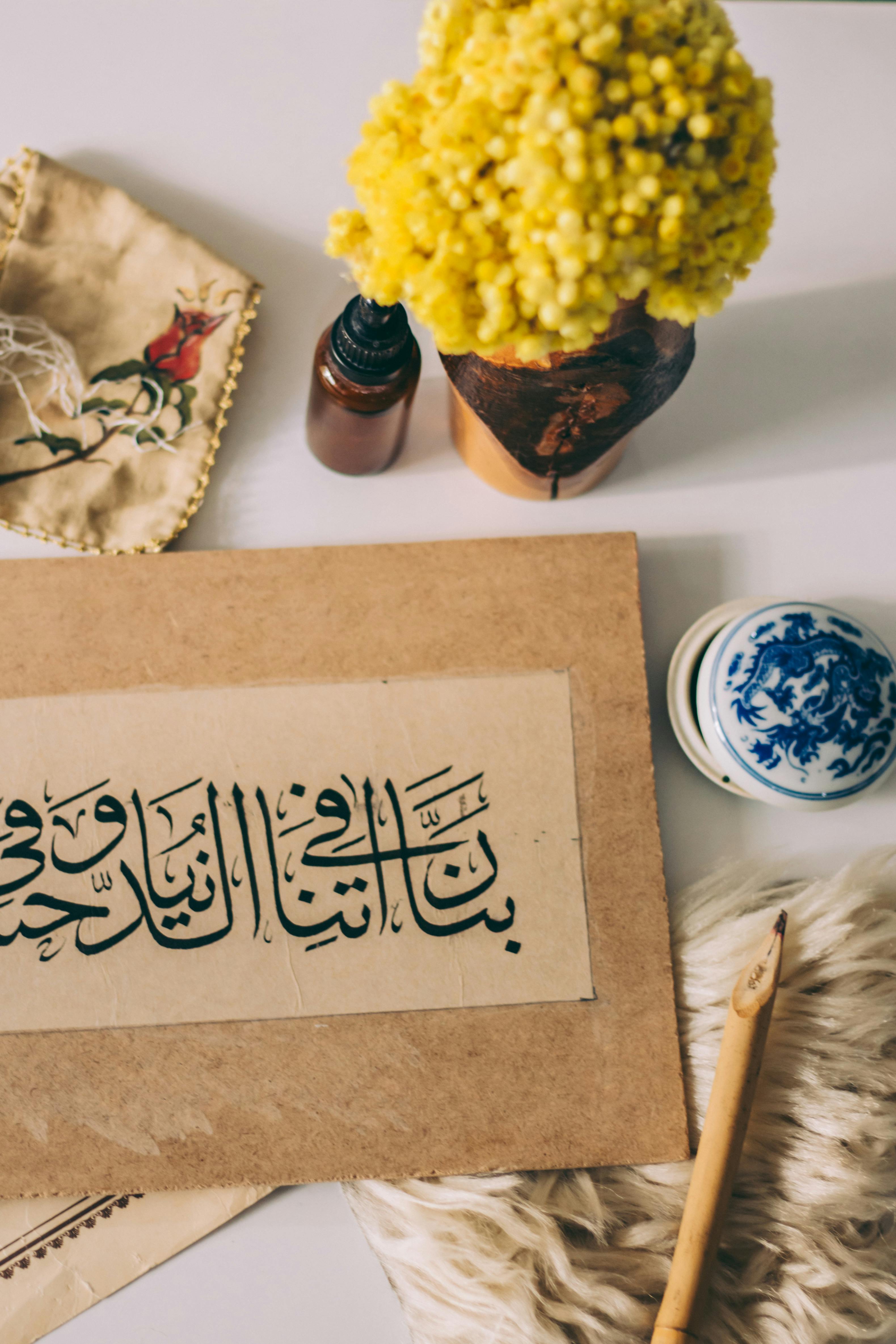 A still life featuring traditional calligraphy, yellow flowers, and decorative items.