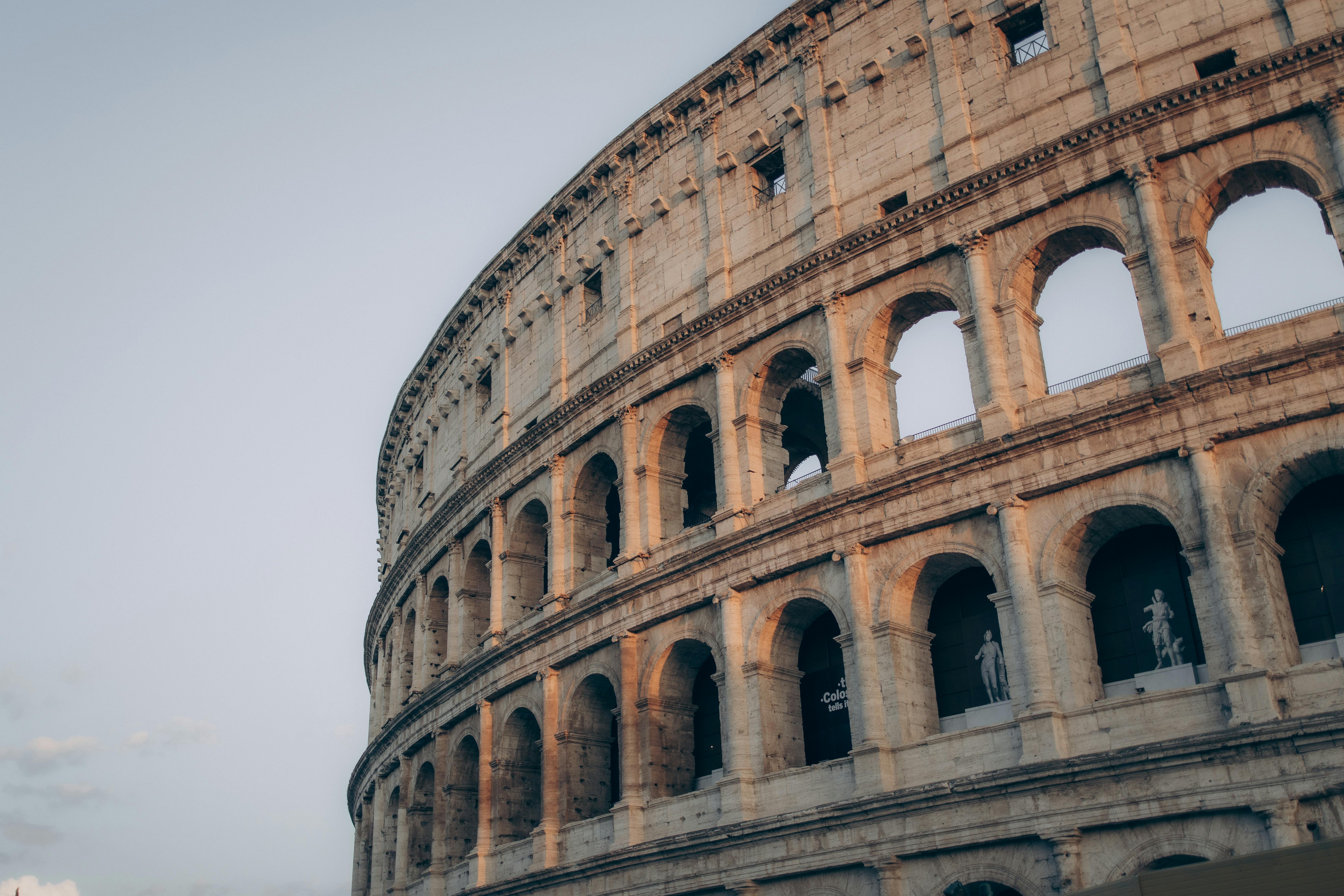 Beautiful view of the Colosseum in Rome during sunset, highlighting its ancient arches and grandeur.