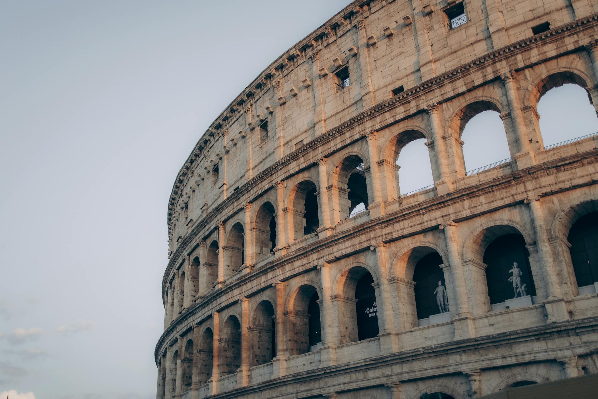 Beautiful view of the Colosseum in Rome during sunset, highlighting its ancient arches and grandeur.