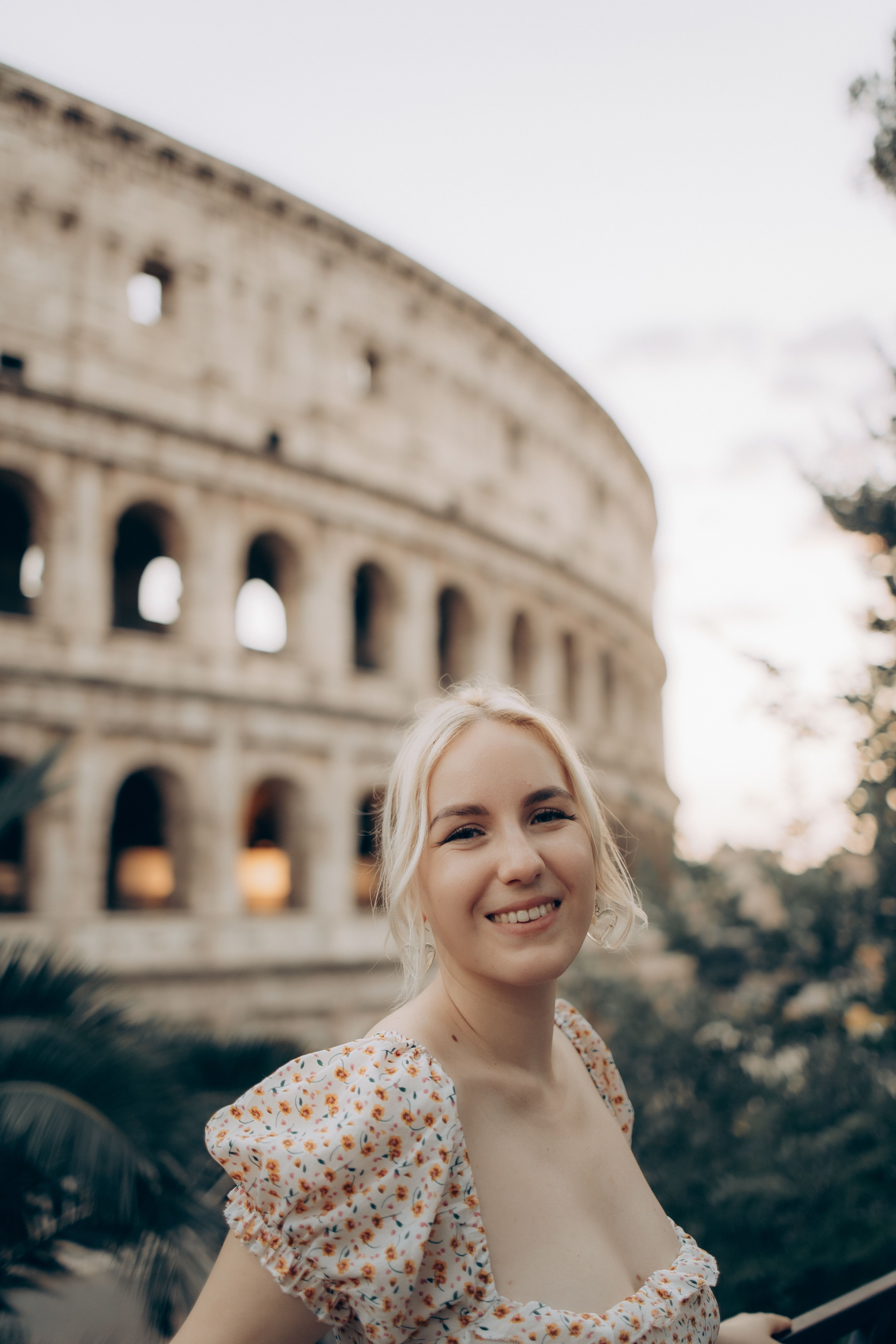 Woman smiling in front of the iconic Colosseum, Rome, Italy, during sunset.