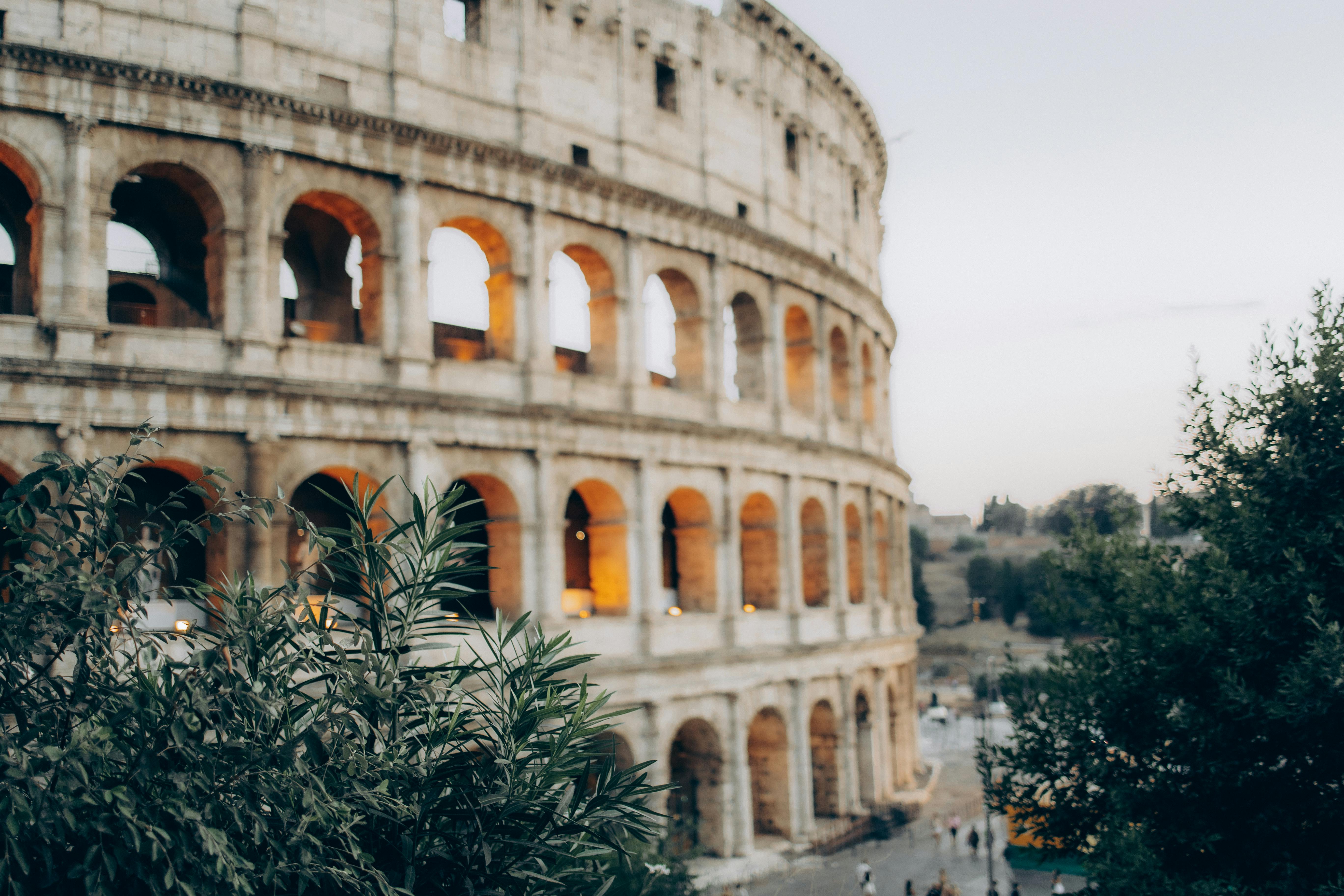 gratis Prachtig uitzicht op het Colosseum in Rome tijdens zonsondergang, met nabijgelegen groen. Stockfoto