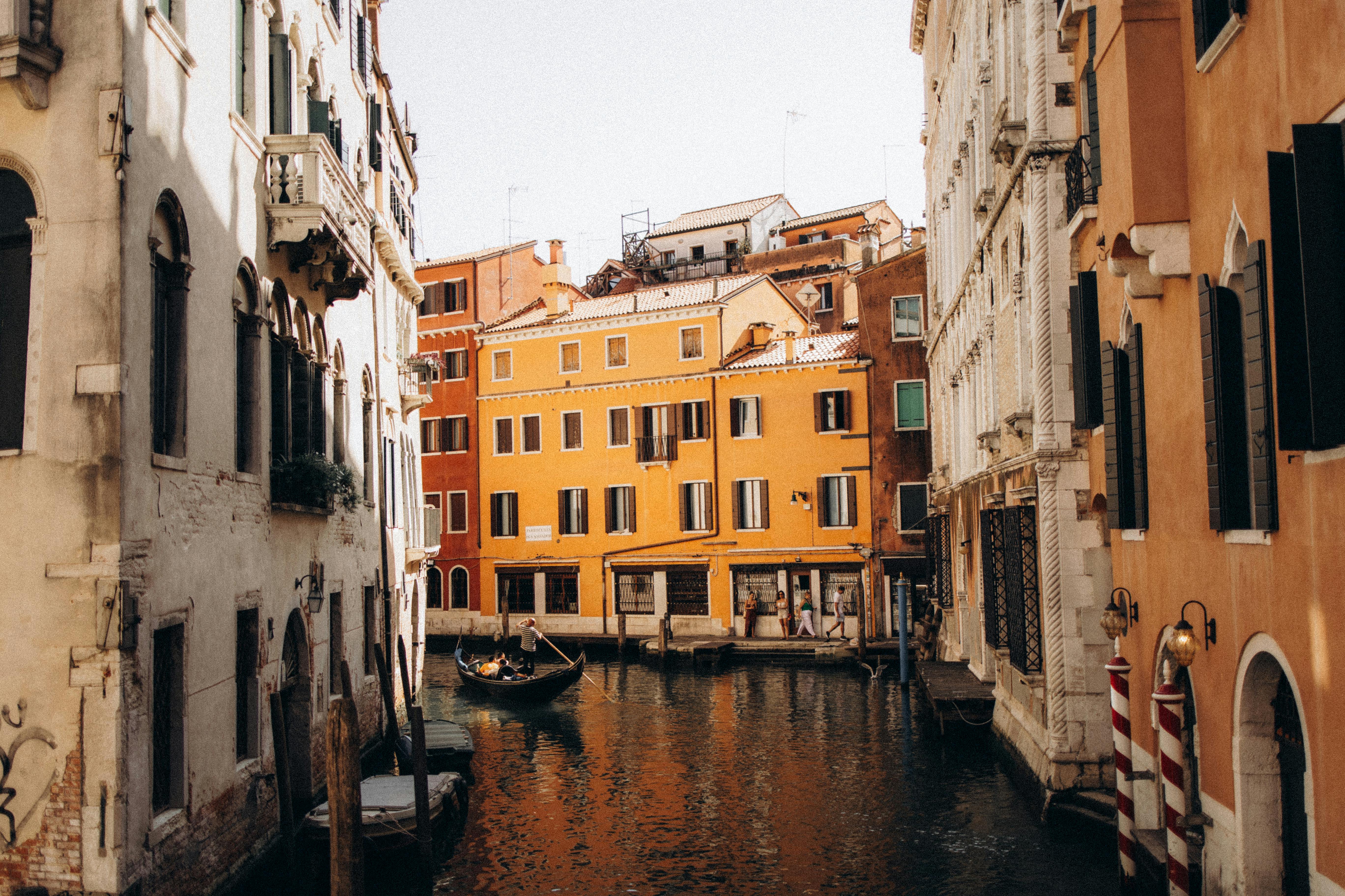 Picturesque Venice canal scene with vibrant buildings and a gondola under the clear sky.
