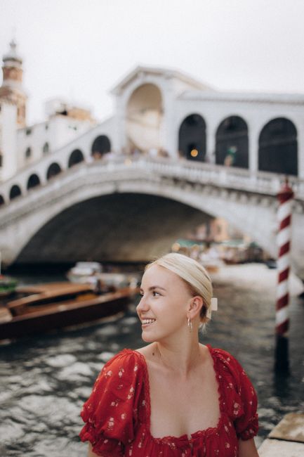 Smiling woman in front of the historic Rialto Bridge in Venice, Italy.