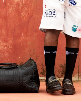 Street style fashion with a black duffel bag and graphic shorts.