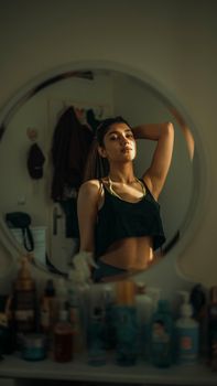 Confident young woman poses in front of a mirror, offering a fashion-forward and introspective look.