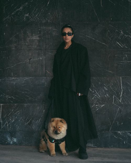Free A stylish woman in black with a Chow Chow dog against a marble backdrop, exuding modern elegance. Stock Photo