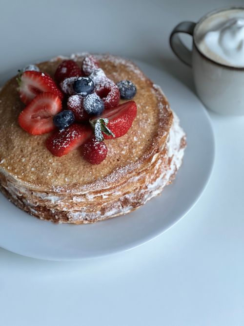 Free Fresh layered pancake topped with berries and powdered sugar, served with creamy coffee. Stock Photo
