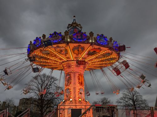 Free Colorful carousel lit up during twilight in an urban park setting. Fun and festive atmosphere. Stock Photo