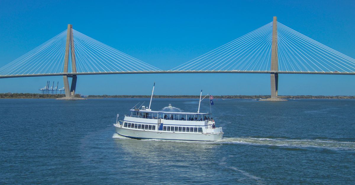 White ferry boat sails near Arthur Ravenel Jr. Bridge in Charleston.