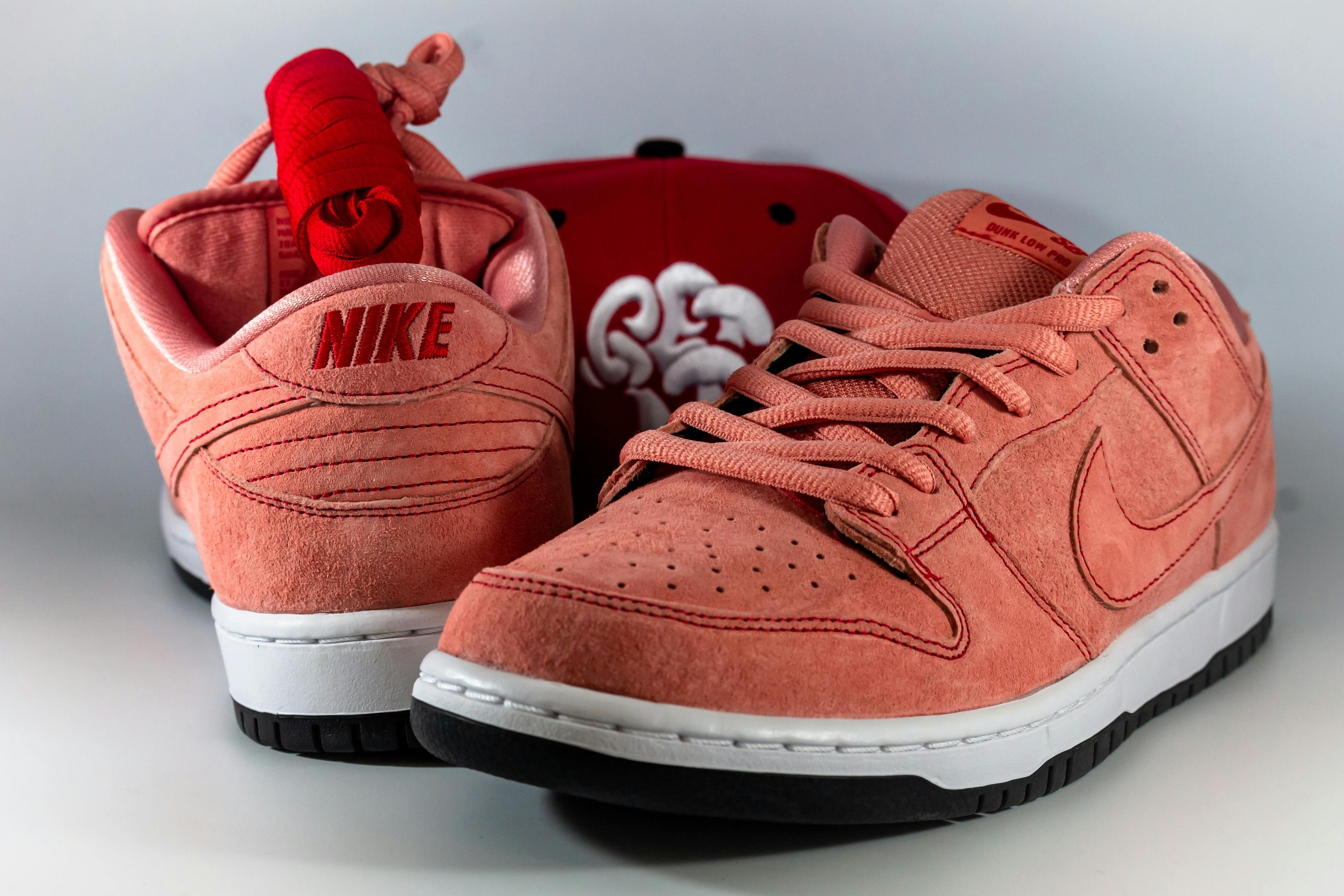 Close-up of trendy pink Nike sneakers paired with a red cap. Perfect for fashion enthusiasts.