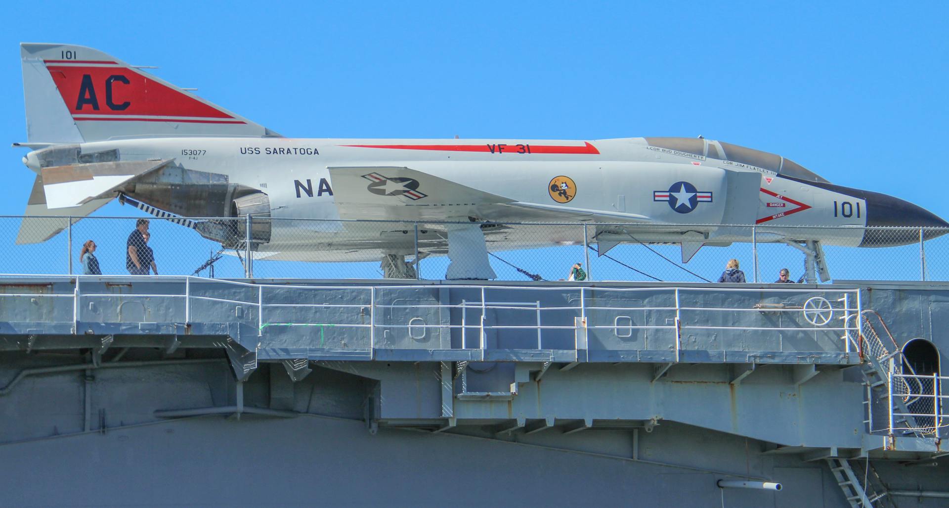 Fighter jet displayed on the USS Saratoga aircraft carrier deck with visitors exploring the site.