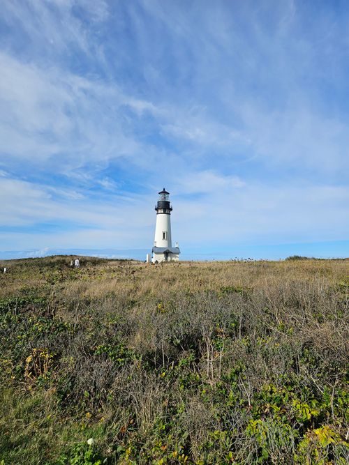 Free Scenic view of a lighthouse standing tall on a coastal cliff under a clear blue sky. Stock Photo