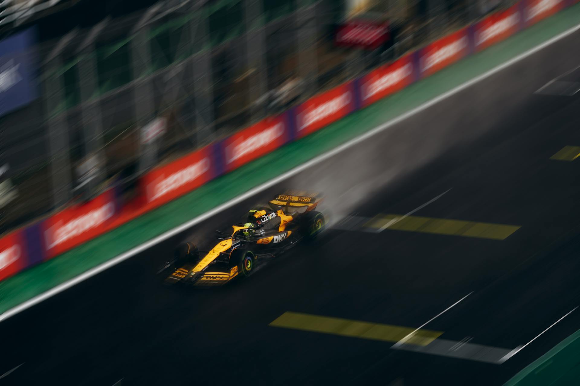 Dramatic capture of a high-speed race car on a rainy track, showcasing motion and speed.