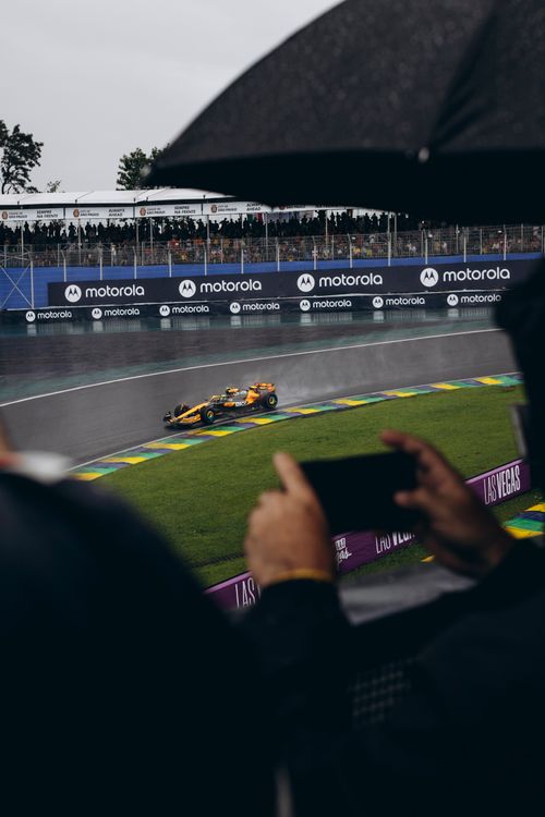 Free Dramatic scene of a Formula 1 car racing on a wet track surrounded by spectators. Stock Photo