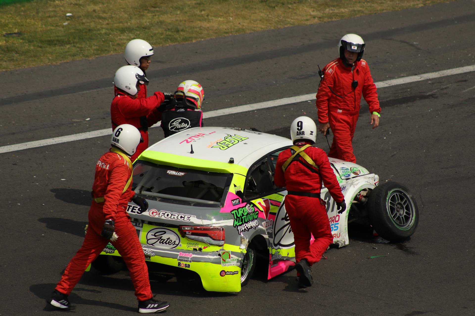 Racecar crash with crew inspecting damage on Mexico City track.