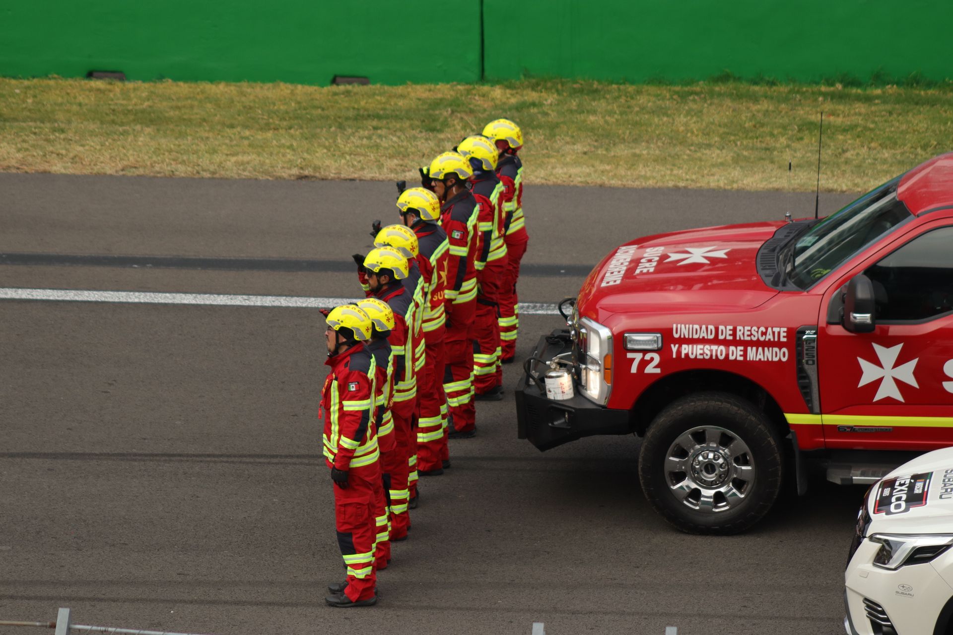 Rescue personnel in uniform lineup beside command vehicle in Mexico City.