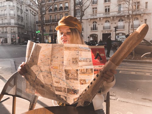 Free Photo of Sitting Woman Holding Baguette While Reading a Map Stock Photo