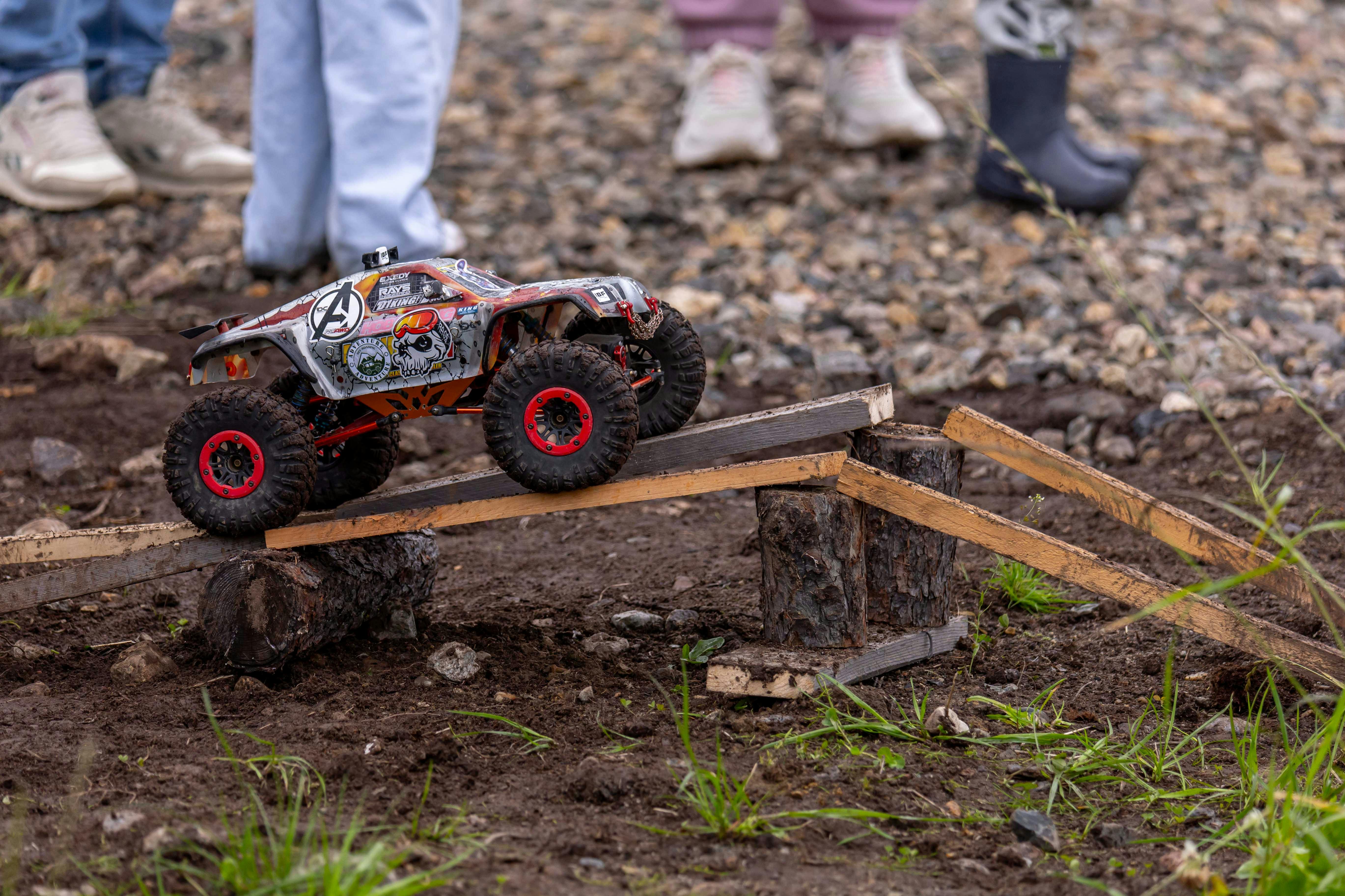 A remote control car navigates a wooden obstacle course outdoors, showcasing its off-road abilities.
