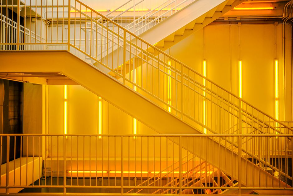 A contemporary staircase with bright yellow neon lights creating an industrial ambiance.