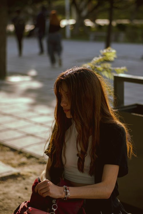 Young Woman in Urban Park with Sunlit Hair · Free Stock Photo
