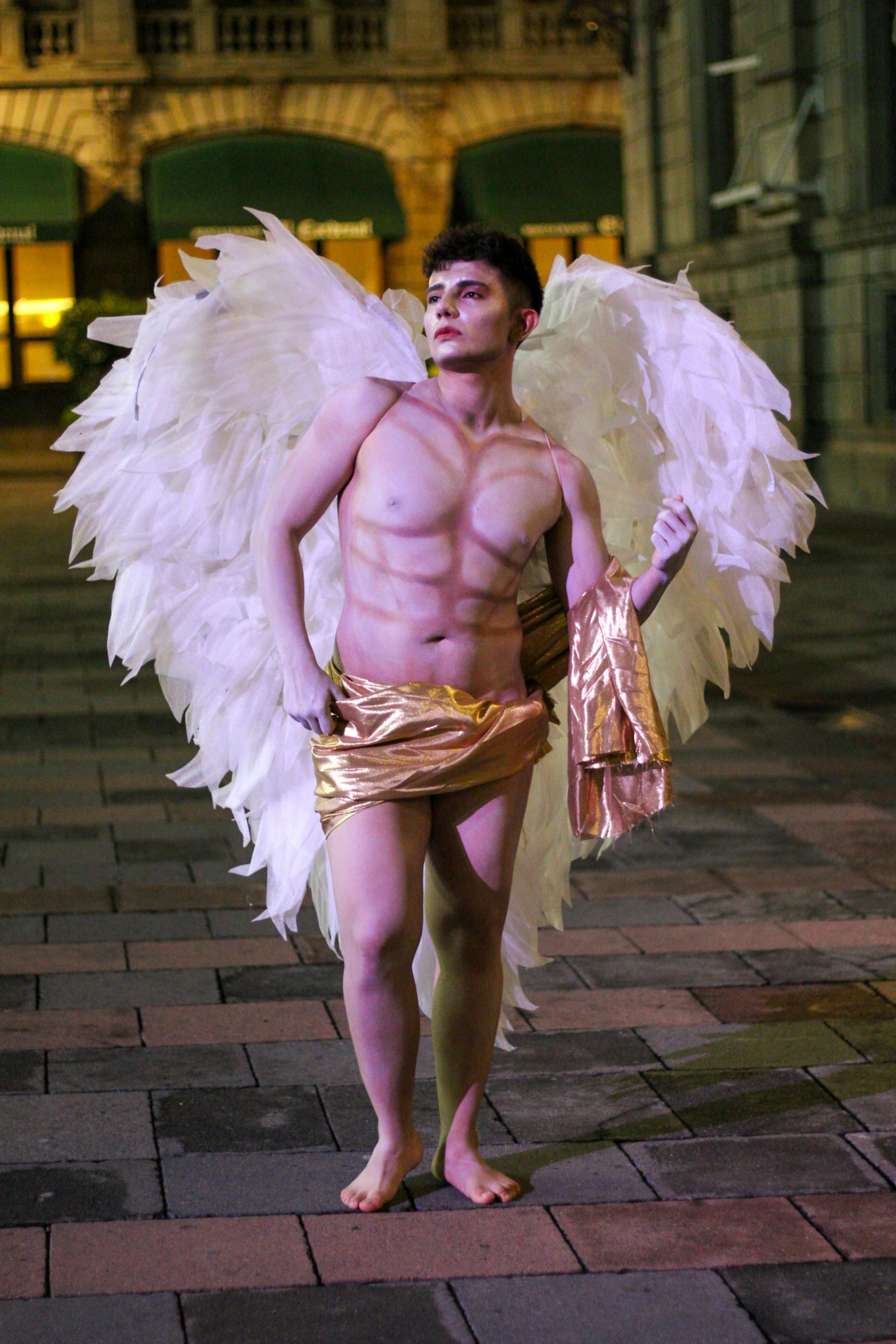 De franc Model masculí vestit d'àngel amb ales de nit a l'aire lliure. Foto d'estoc