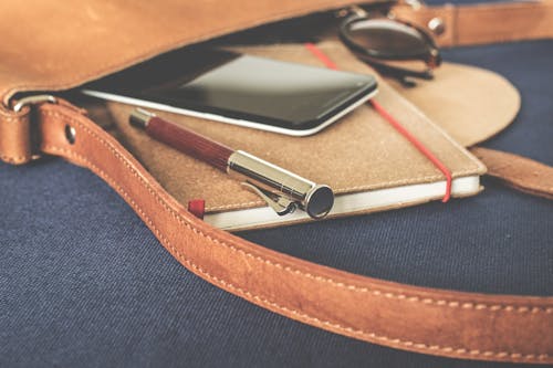 Free Smartphone Displaying Black Screen on Notebook Beside Pen and Sunglasses Stock Photo