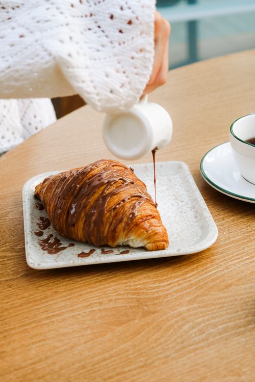 Free A warm croissant drizzled with chocolate sauce in an Adana café setting. Stock Photo