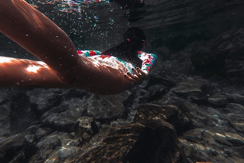 Free Woman Swimming Under Water Above Rocks Stock Photo