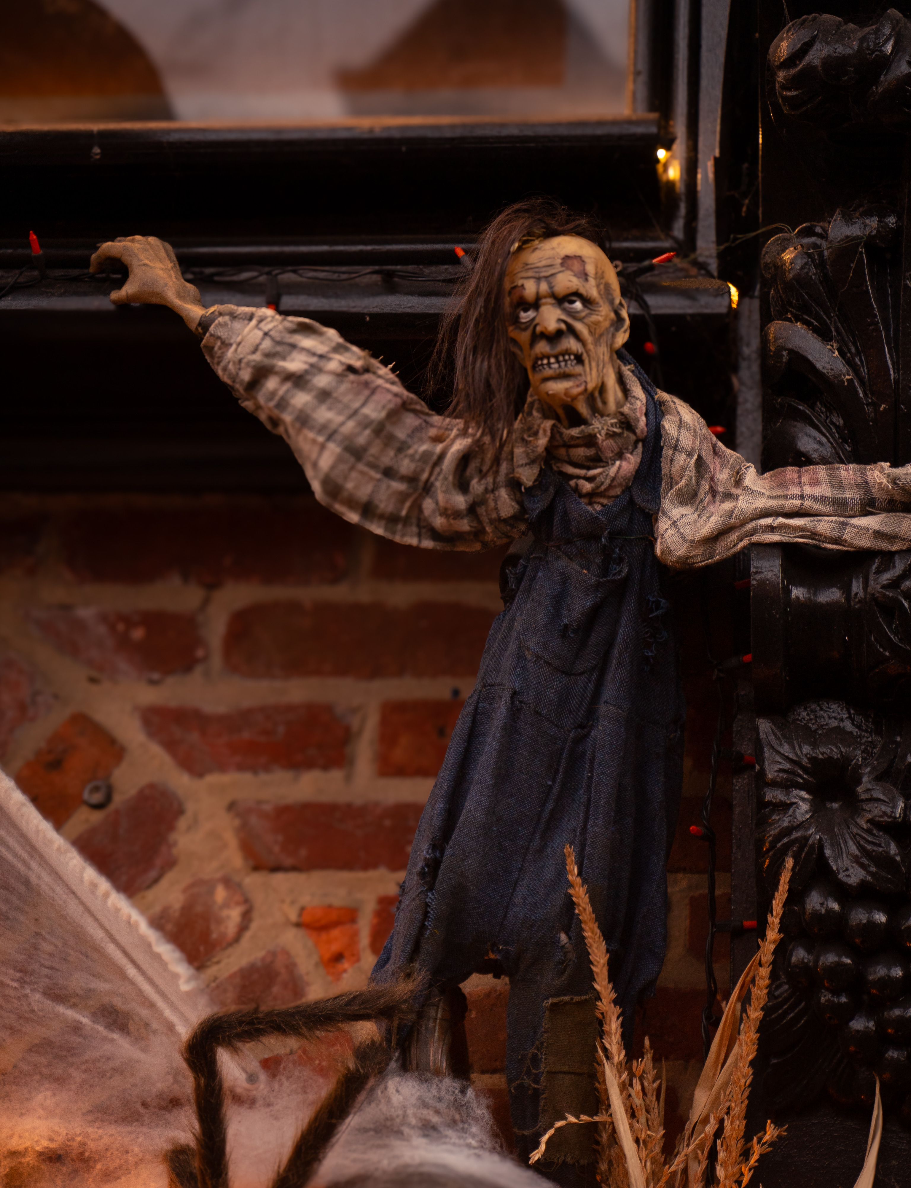 Gratuit Une marionnette effrayante vêtue d'une salopette à carreaux et en jean sur un mur de briques, parfaite pour la décoration d'Halloween. Photos