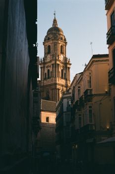 Captivating view of a gothic bell tower framed by classic European architecture in a narrow alley.