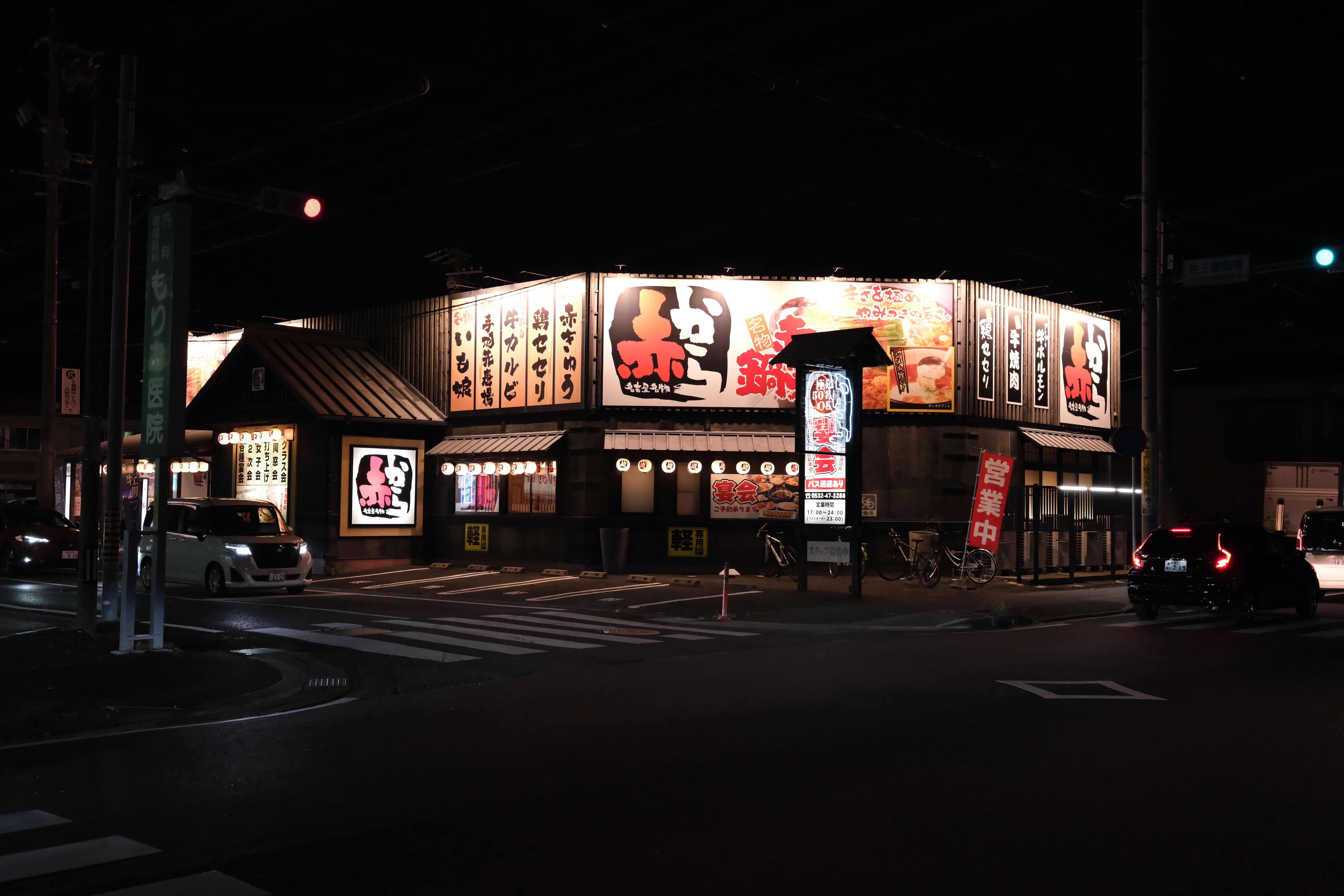 Illuminated Japanese restaurant with vibrant signage at night in Toyohashi, Japan.