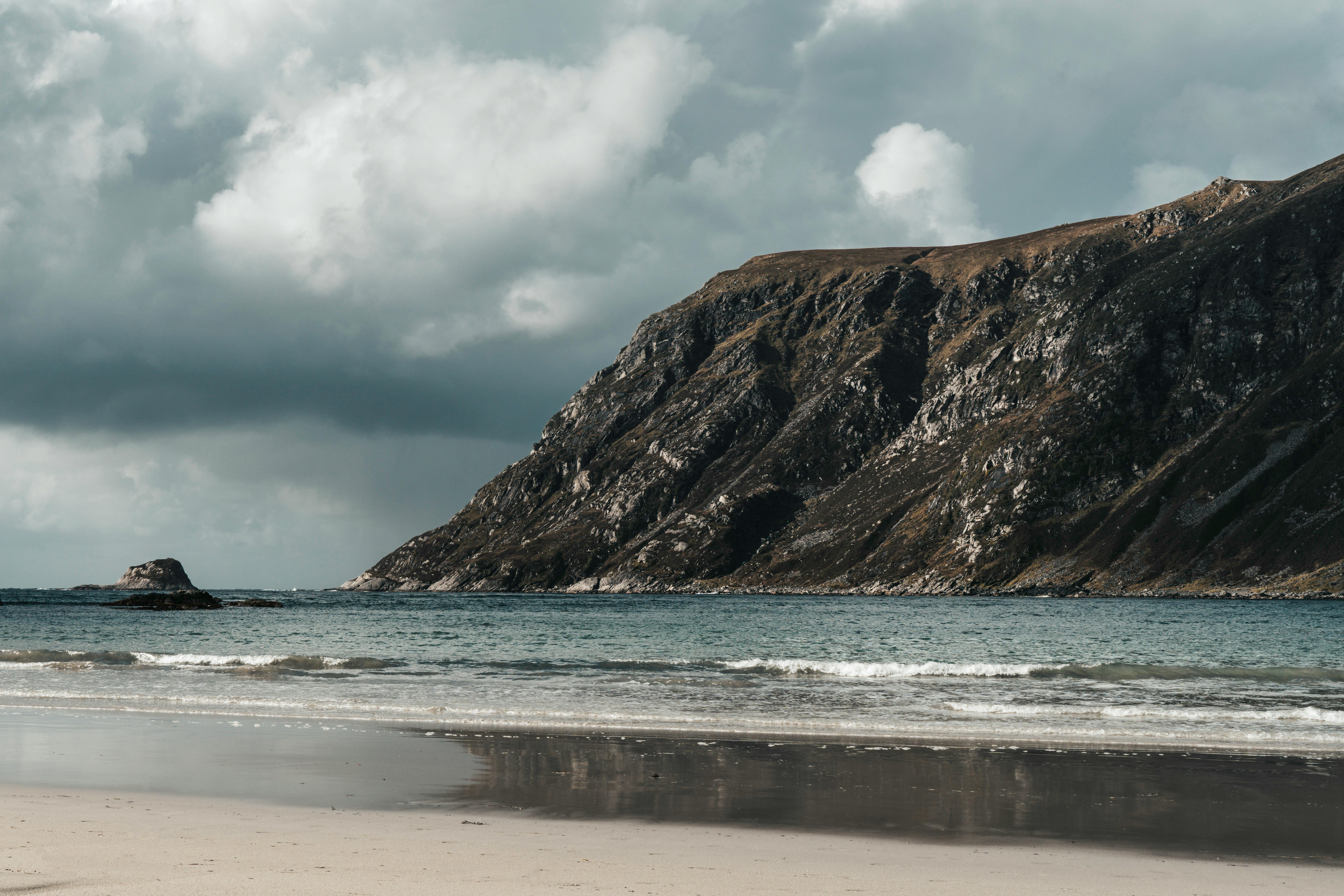 在多云的天空下，喜怒无常的沙滩上，高耸的海崖风景