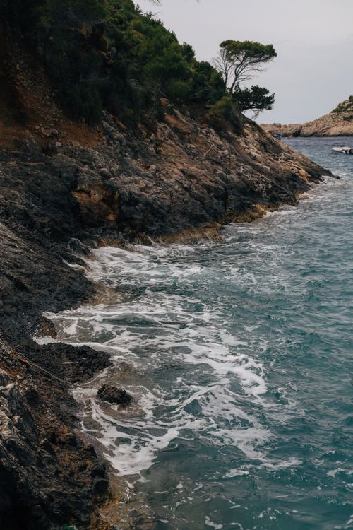 Free A picturesque rocky coastline with waves crashing gently against the shore, evoking tranquility. Stock Photo