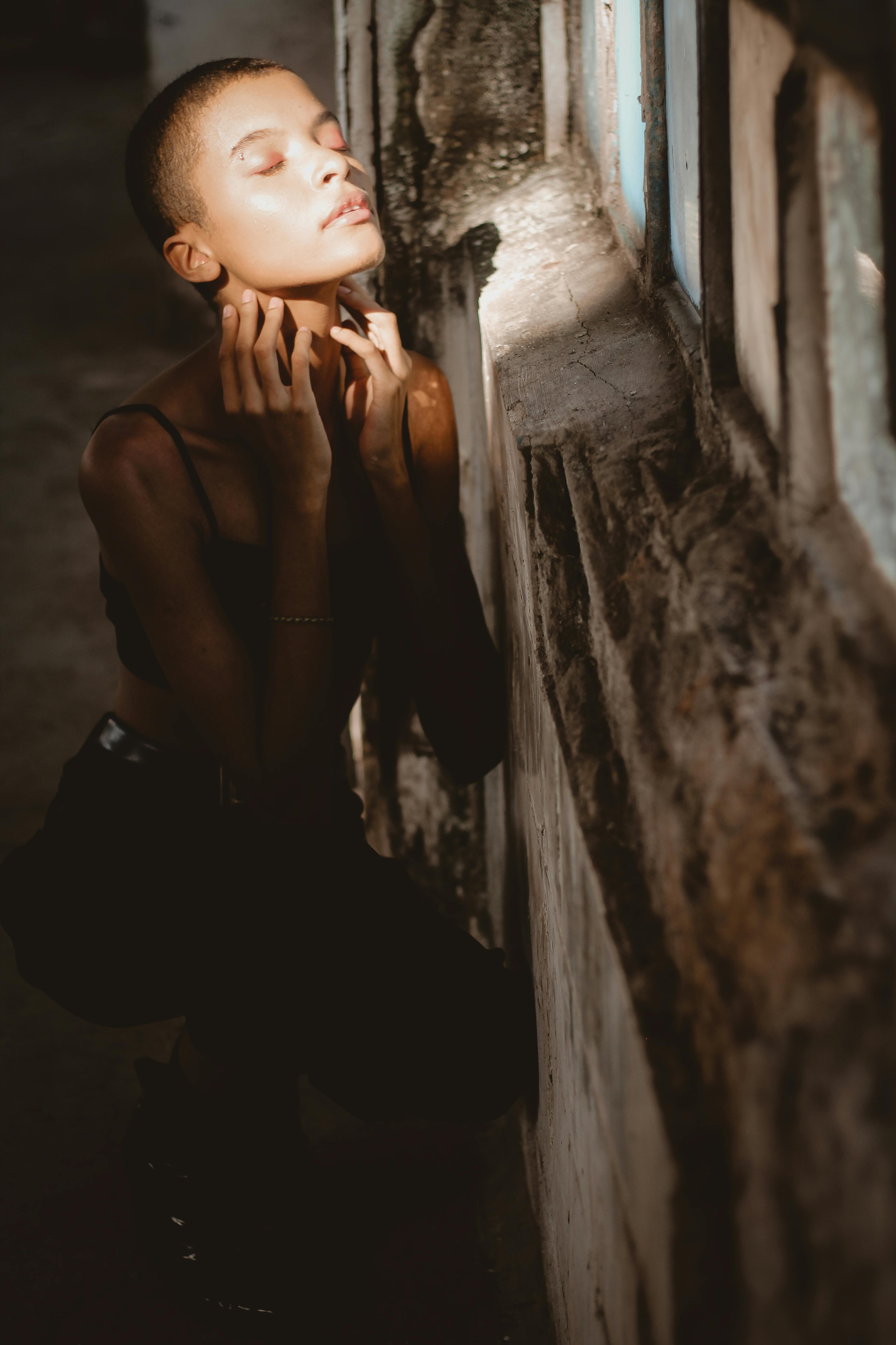 Stylish portrait of a woman posing by a window, highlighting light and shadow.