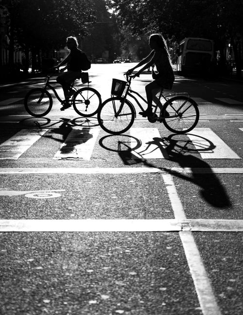 Free Monochrome street photography capturing cyclists silhouetted against the setting sun in Buenos Aires. Stock Photo