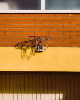 Basketball hoop casting shadow on urban brick wall in Madrid during daytime.