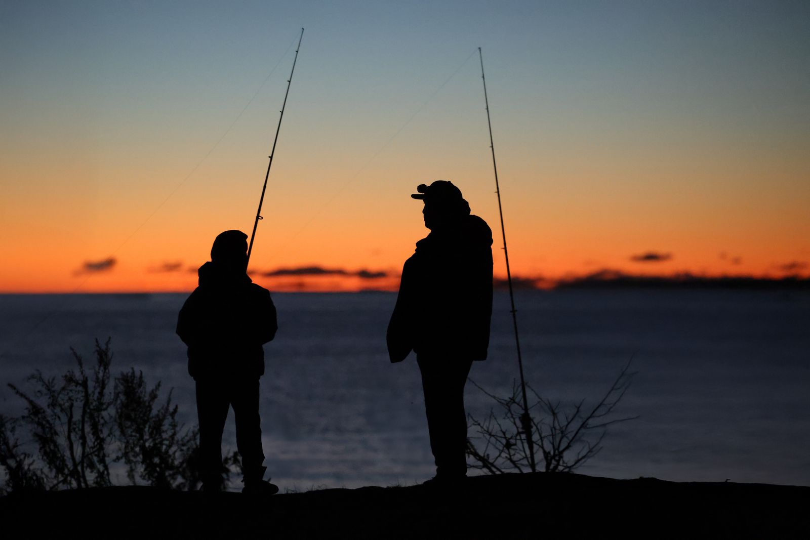 Father and son fishing together as the sun comes up over the sound