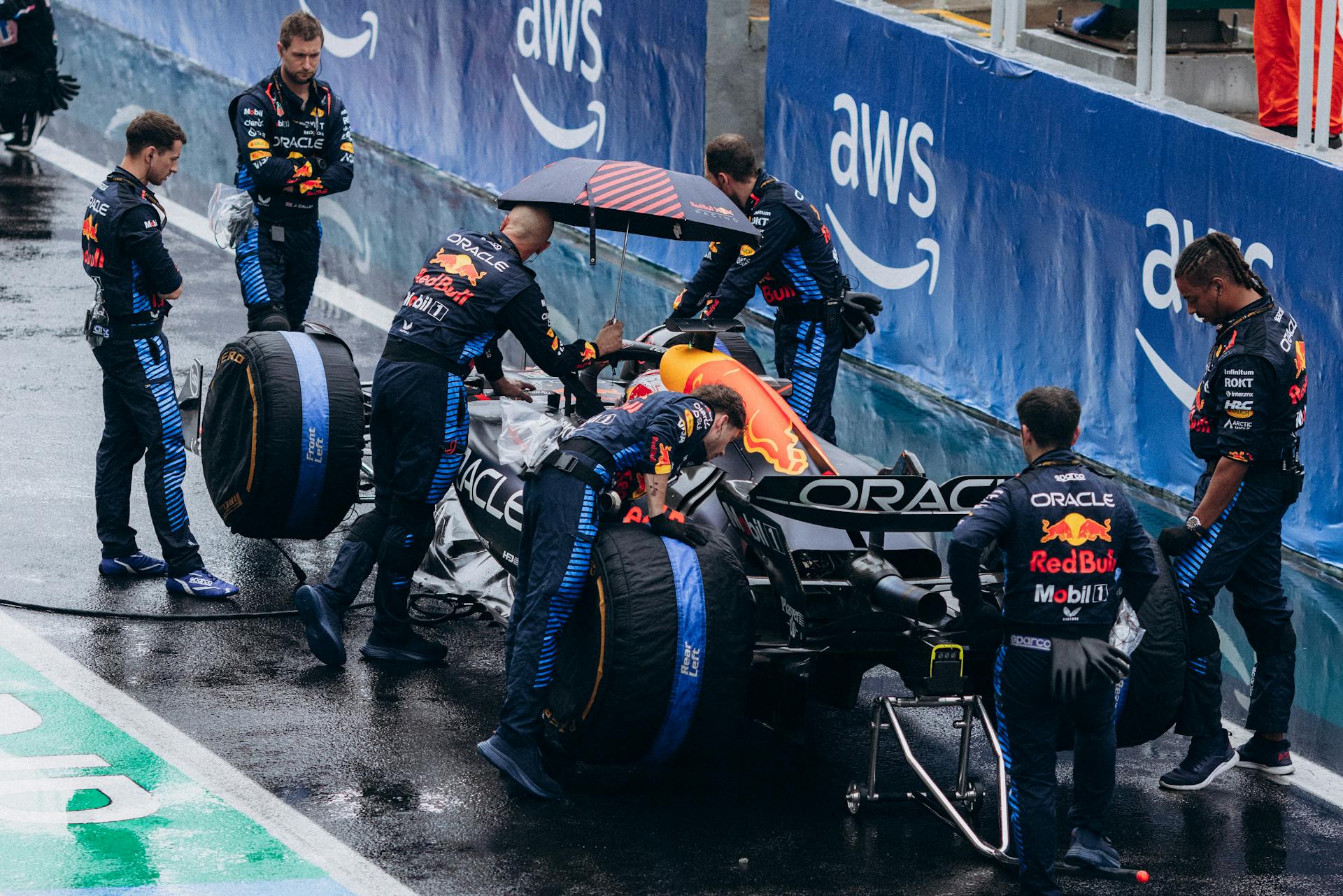 Team working on a Formula 1 car during a wet race pit stop, showcasing teamwork and precision.