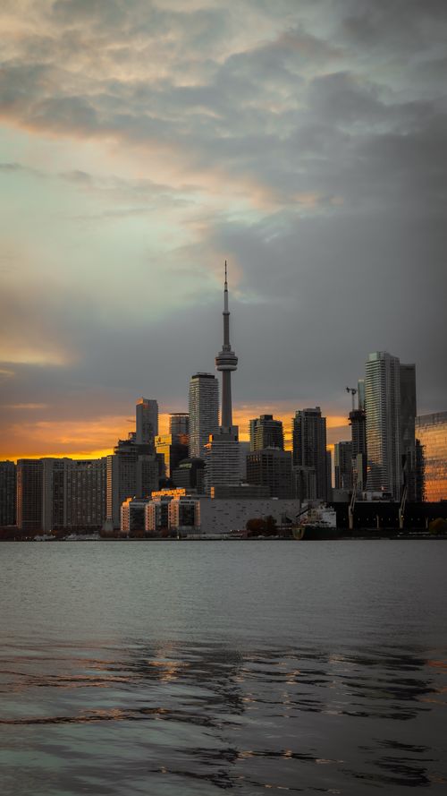 Free Dramatic view of Toronto skyline with CN Tower at sunset, reflecting on lake. Stock Photo