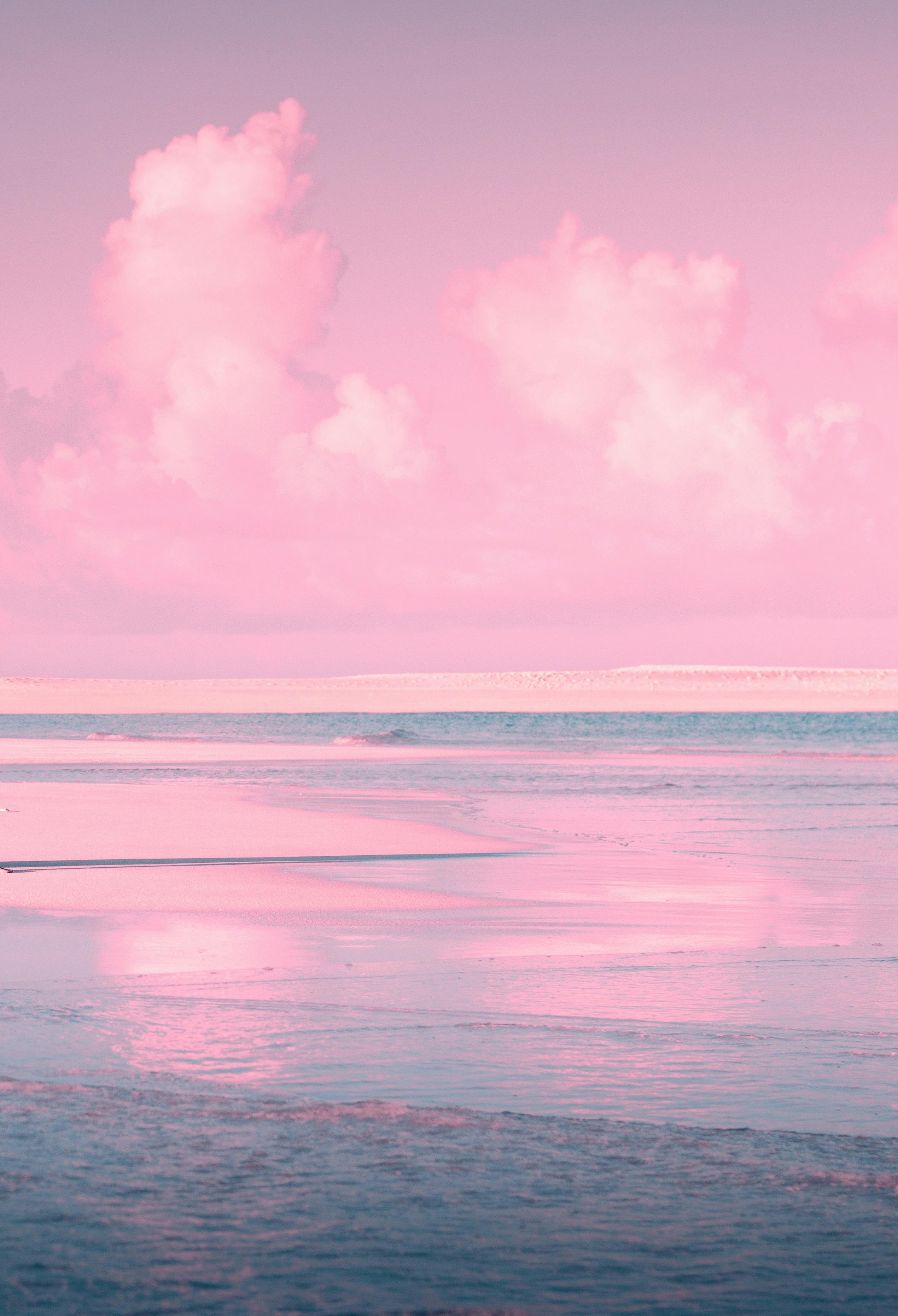 Serene beachscape with pink clouds and reflections at dawn.