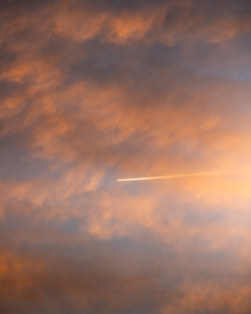 Free Vibrant sunset clouds with a plane contrail in Hamburg's sky, captured during golden hour. Stock Photo