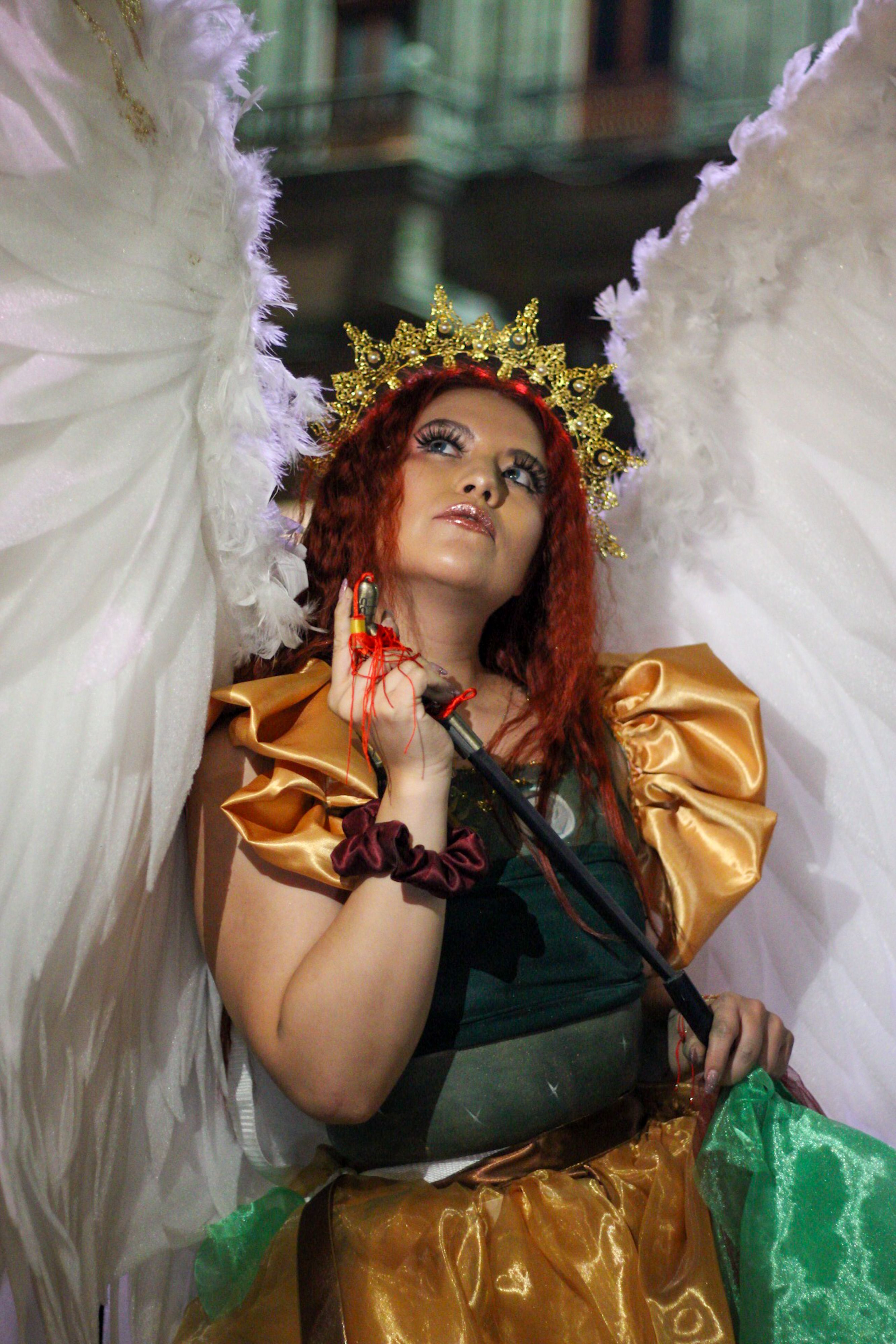 Person in elaborate angel costume with wings and halo photographed during a night event.