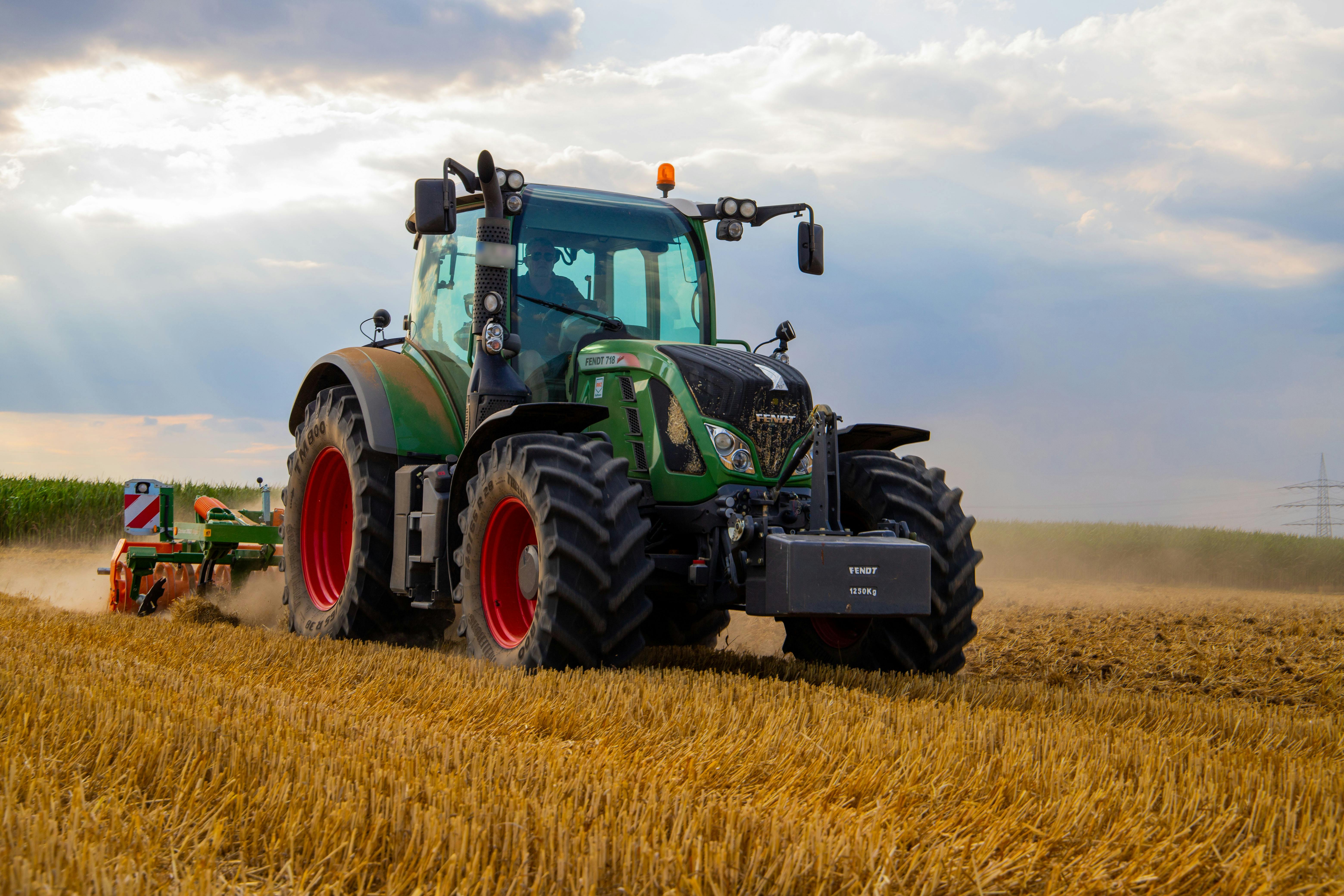 green tractor plowing the fields on focus photography