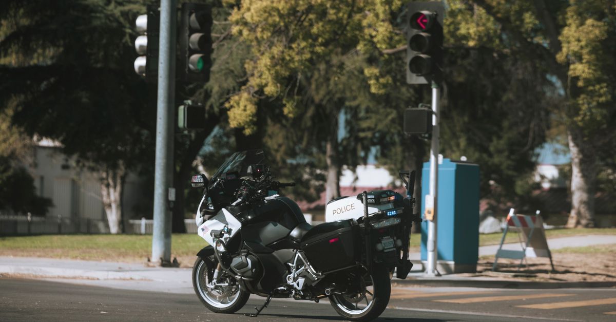 A police motorcycle stopped at a city intersection with traffic lights.