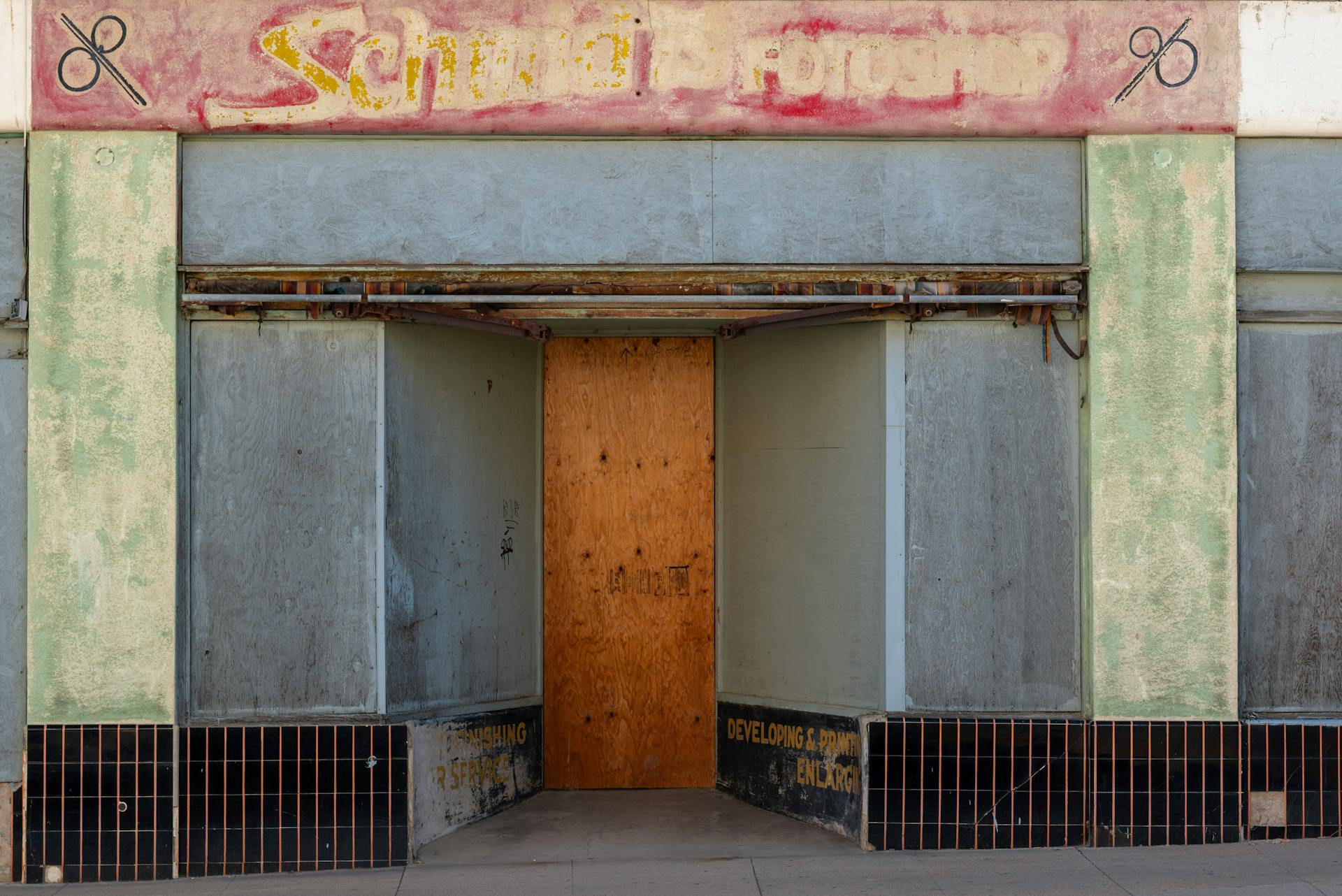 An old, abandoned storefront with a boarded-up entrance and faded signage.